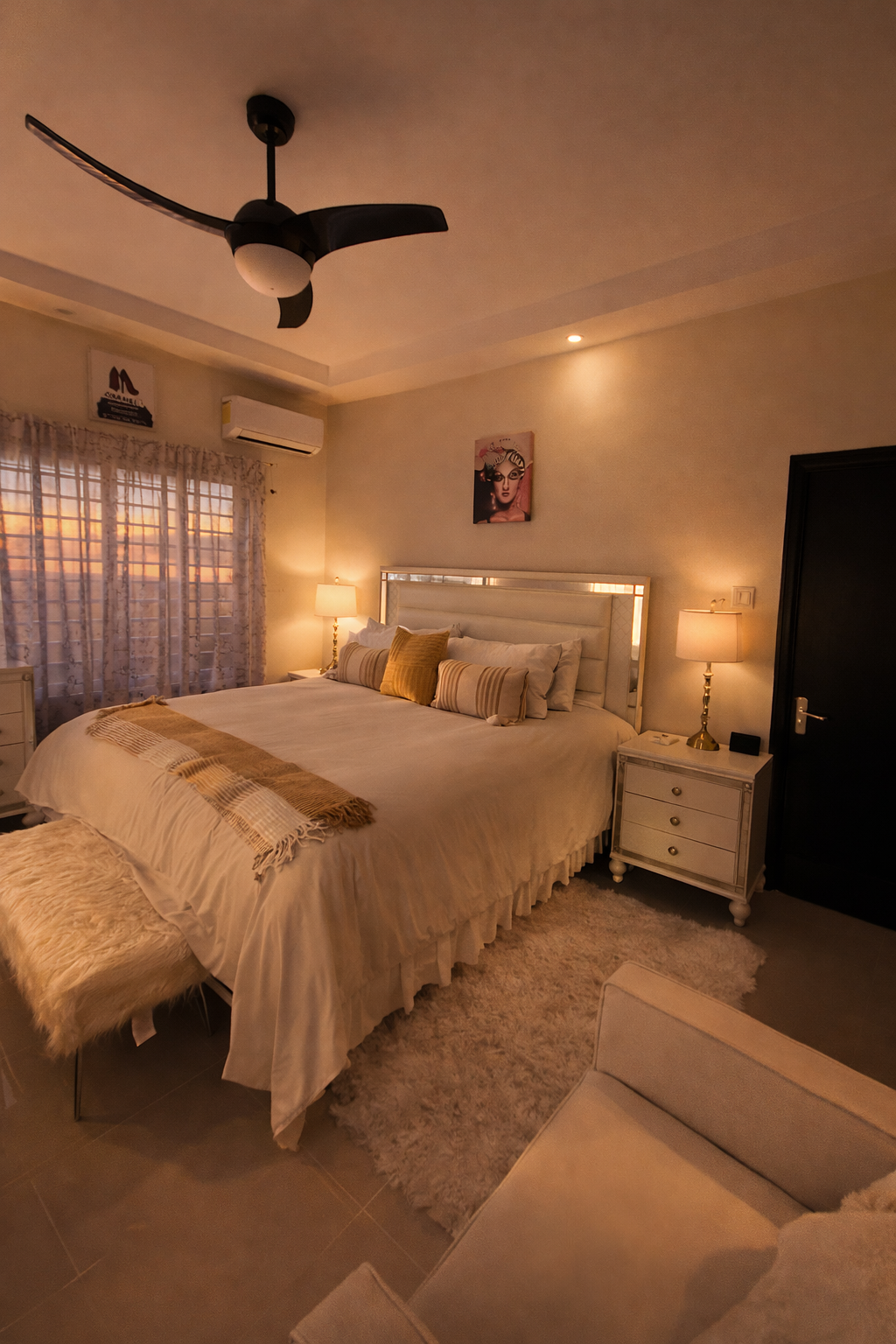 The king bedroom in warm evening light with a dressed king bed, mirrored furniture and ceiling fan