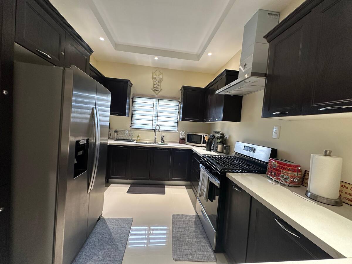 The villa kitchen with dark cabinetry, refrigerator, stove, microwave and countertop appliances
